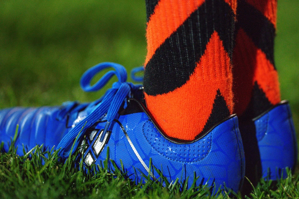 Close up of a ball kid’s cleats and socks on the sideline